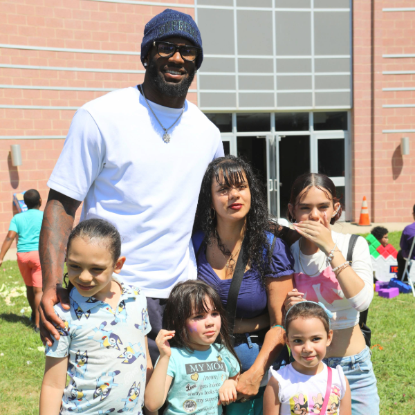 A group of people posing outside a building on a sunny day.