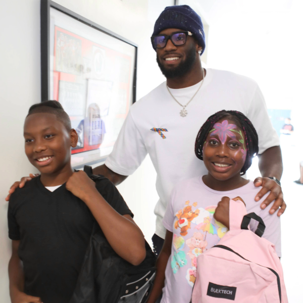 Three people smiling with backpacks, indoors
