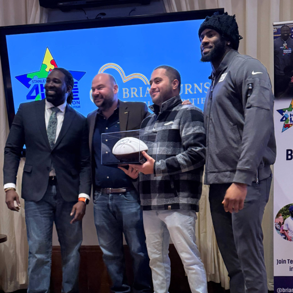 Four men displaying a football case near Brian Burns event logos.