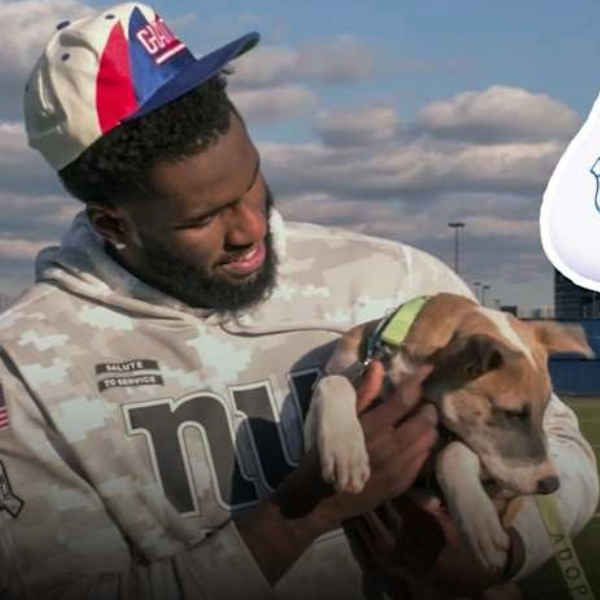 Brian Burns in a camouflage hoodie holding a brown and white puppy with a green collar.